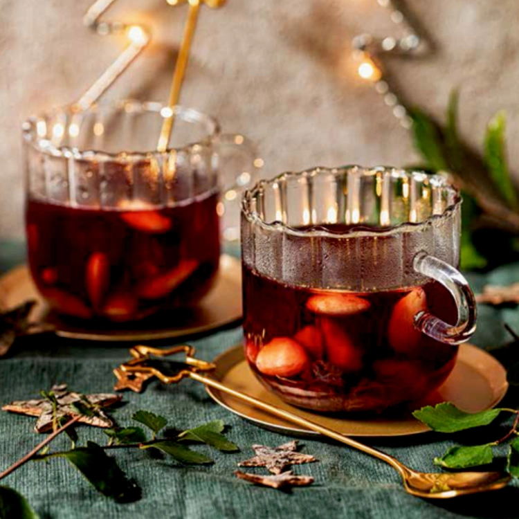 Zwei Gläser gefüllt mit rotem Früchtepunsch in stimmungsvollem Weihnachtssetting.