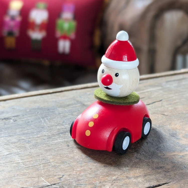 Kleiner Holznikolaus in einem Auto auf einem Tisch.