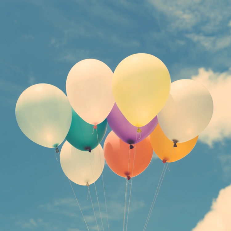 bunte Luftballons steigen vor einem blauen himmel mit weißen Wolken auf